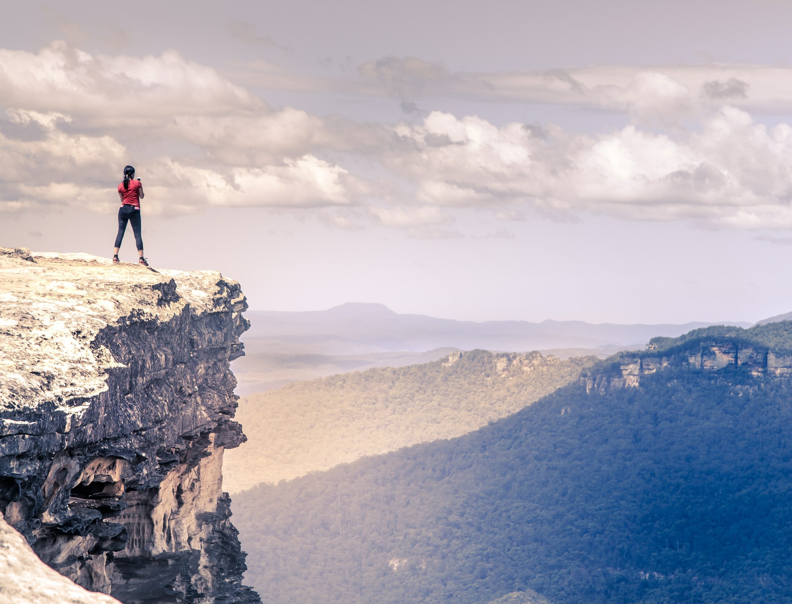 Women in red top standing at the top of a cliff