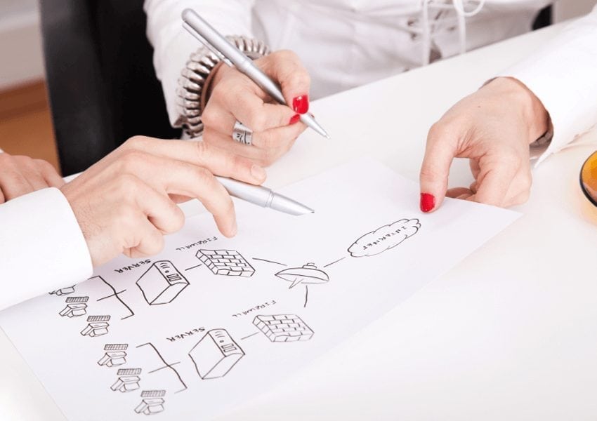 Two people discussing a paper, holding pens