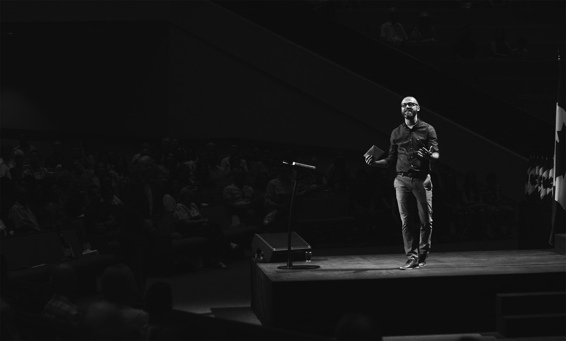 Black and white picture of man present on a stage to crowd